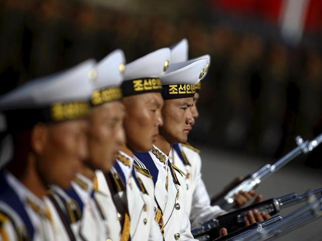 Soldiers carry their weapons marching past a stand with North Korean leader Kim Jong Un. (REUTERS)