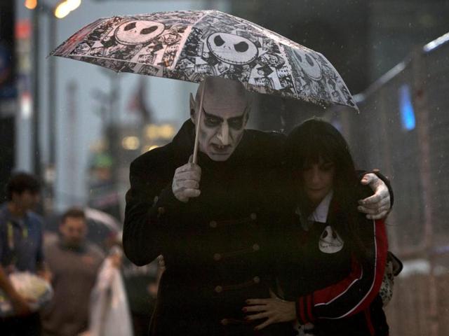 Ken and Lori Caiafa, dressed as Nosferatu and Vampirella, walk through the rain. (REUTERS)