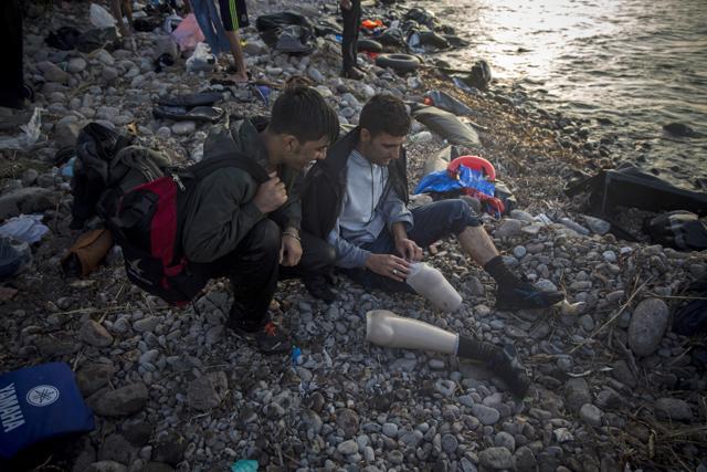 An Afghan refugee prepares his prosthetic leg to start walking immediately after arriving on a dinghy to Lesbos from the Turkish coast. (AP) An Afghan refugee prepares his prosthetic leg to start walking immediately after arriving on a dinghy to Lesbos from the Turkish coast. (AP)
