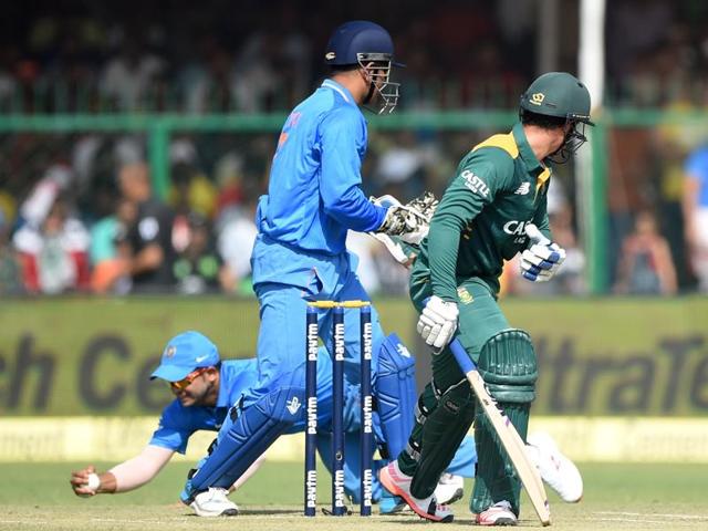 India's captain Mahendra Singh Dhoni, centre, and South Africa's Quinton de Kock, right, look back as India's Suresh Raina takes a catch to dismiss de Kock during the first innings. (AFP Photo)