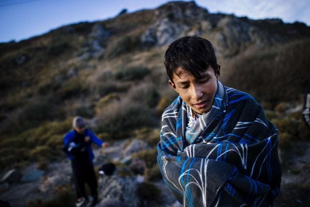 A young man wraps himself in a blanket on a beach shortly after he arrived with other migrants by boat on Lesbos. (AFP) A young man wraps himself in a blanket on a beach shortly after he arrived with other migrants by boat on Lesbos. (AFP)