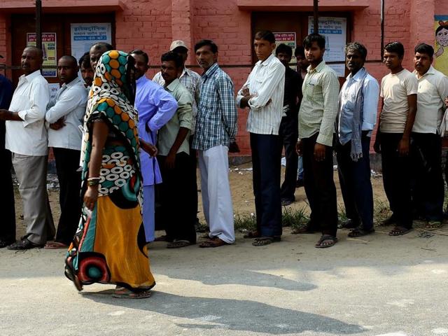 Voters queue to cast their ballots as a woman leaves after polling in the village of Banbira in Samastipur district on October 12, 2015. (AFP)