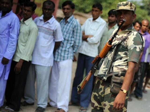 Voters queue to cast their ballots as a security personnel stands guard at a voting centre in the village of Banbira in Samastipur district. (AFP)