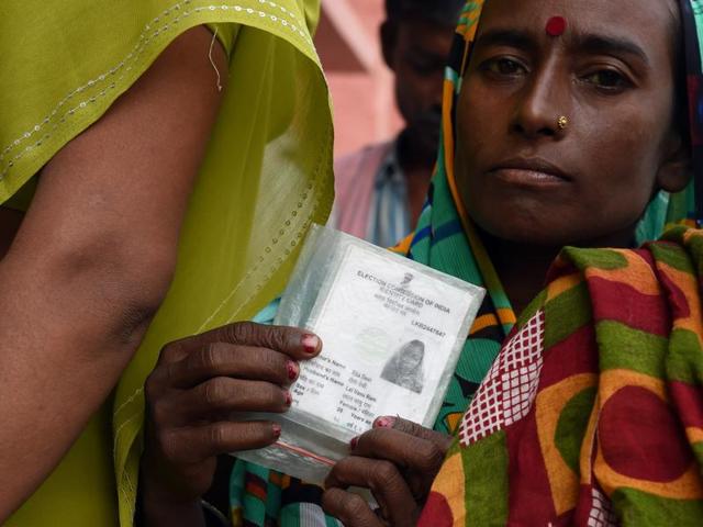 A voter holds up her voting card before casting her ballot at a voting centre in Samastipur . (AFP)