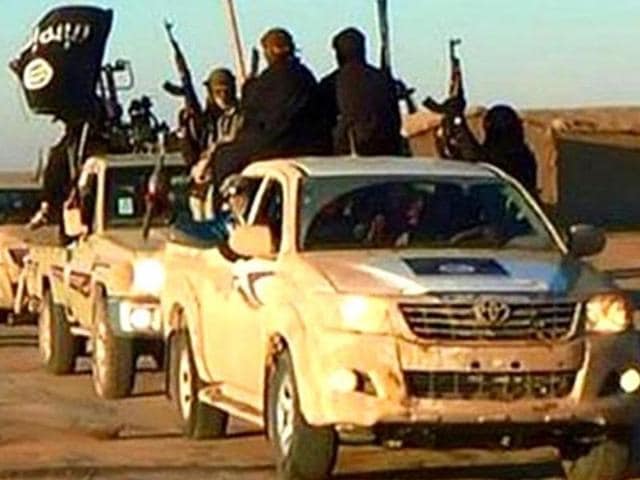 In this undated photo released by a militant website, militants of the Islamic State group hold up their weapons and wave its flags on their vehicles in a convoy on a road leading to Iraq, while riding in Raqqa city in Syria. (Militant website via AP) In this undated photo released by a militant website, militants of the Islamic State group hold up their weapons and wave its flags on their vehicles in a convoy on a road leading to Iraq, while riding in Raqqa city in Syria. (Militant website via AP)