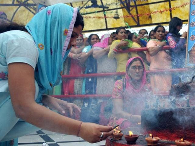 A devotee offering prayers as other stands in queue on the first day of Navratras at Bahu fort temple in Jammu on Tuesday. (Nitin Knaotra / HT)