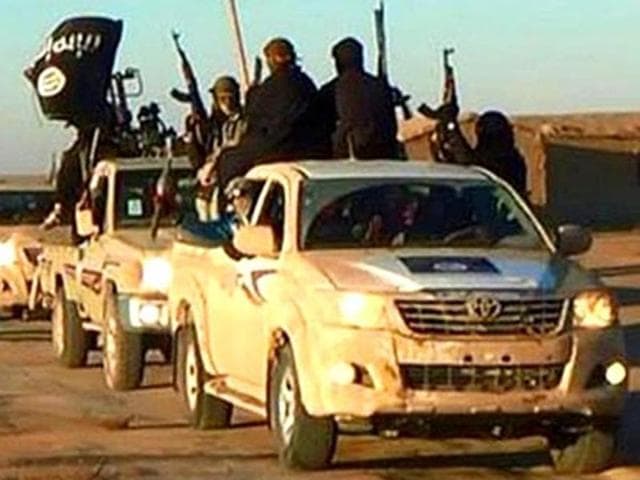 In this undated photo released by a militant website, jihadists of the Islamic State group hold up their weapons and wave its flags on their vehicles in a convoy on a road leading to Iraq, while riding in Raqqa city in Syria. ((Militant website via AP)) In this undated photo released by a militant website, jihadists of the Islamic State group hold up their weapons and wave its flags on their vehicles in a convoy on a road leading to Iraq, while riding in Raqqa city in Syria. ((Militant website via AP))