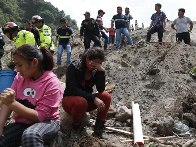 Residents watch rescue efforts after a mudslide hit Santa Catarina Pinula, on the outskirts of Guatemala City, Friday, Oct. 2, 2015. Heavy rain provoked a hillside to collapse, affecting dozens of homes. (AP Photo)
