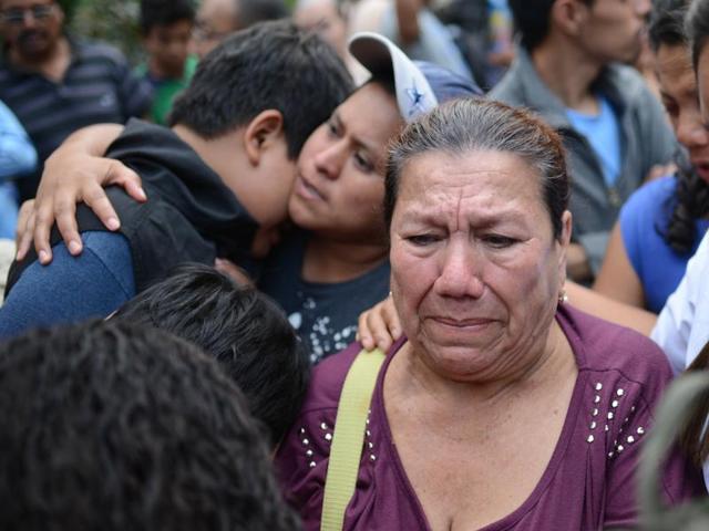Friends and relatives wait for information outside a provisional morgue where the bodies recovered from the site of a landslide have been taken. The hill that towers over the Santa Catarina Pinula neighborhood known as Cambray, collapsed late Thursday after heavy rains, burying several houses with dirt, mud and rocks. (AP Photo)