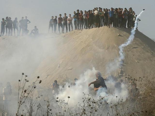 A Palestinian protester returns a tear gas canister fired by Israeli troops during clashes near the border with Israel, in the east of Gaza City. (REUTERS) A Palestinian protester returns a tear gas canister fired by Israeli troops during clashes near the border with Israel, in the east of Gaza City. (REUTERS)