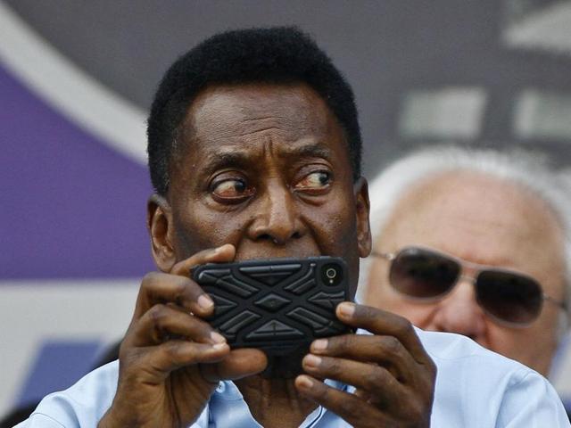 Former Brazilian footballer Pele takes a photograph with his mobile phone before the start of the Under-17 boys final match of the Subroto Cup, in New Delhi, India, on Friday. (Sanjeev Verma/HT Photo)