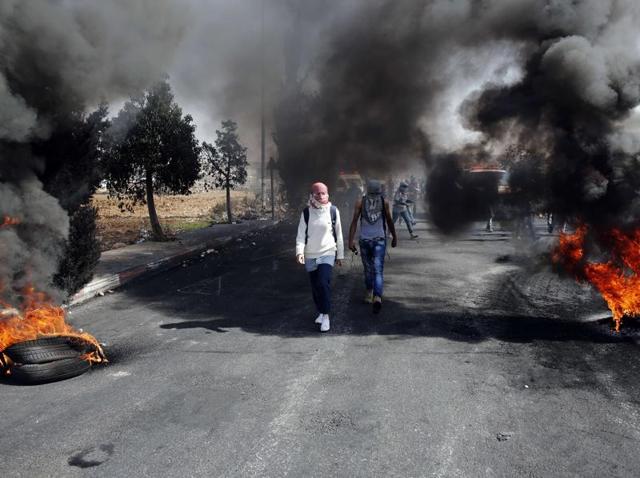 Palestinian protesters walk between burning tires during clashes with Israeli security forces near the Beit El settlement on the outskirts of Ramallah. (AFP) Palestinian protesters walk between burning tires during clashes with Israeli security forces near the Beit El settlement on the outskirts of Ramallah. (AFP)
