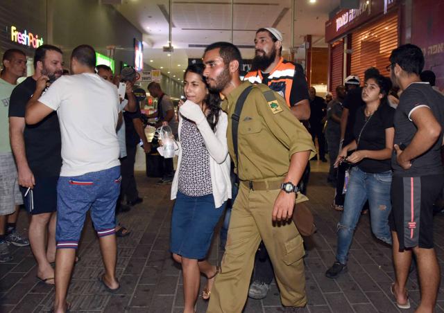 A woman is comforted as others react at the main bus station in the southern Israeli city of Beersheva on October 18, 2015, after a suspected Palestinian gunman armed with a pistol and a knife opened fire on people at the station. (AFP Photo)