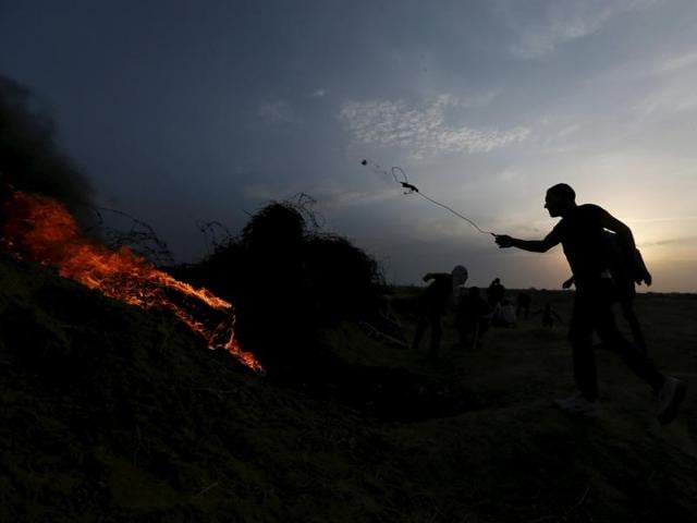 A Palestinian protester uses a sling to hurl stones towards Israeli troops during clashes near the border between Israel and Central Gaza Strip. (Reuters Photo)