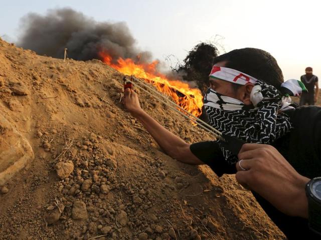 A Palestinian protester uses a slingshot to hurl stones towards Israeli troops during clashes near the border between Israel and Central Gaza Strip. (Reuters Photo)