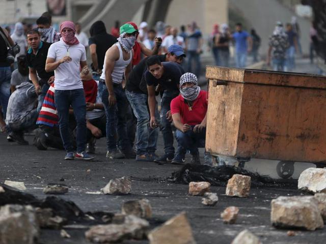 Palestinian protesters take cover during clashes with the Israeli troops near the Jewish settlement of Bet El, near the West Bank city of Ramallah. (Reuters Photo)
