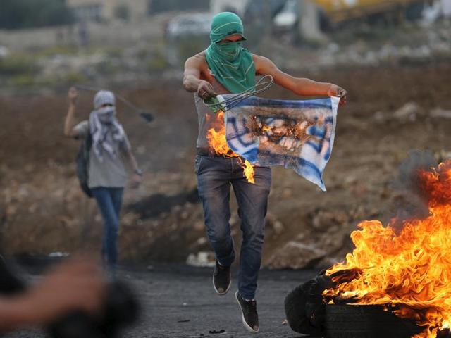 A Palestinian protester burns a replica flag during clashes with Israeli troops near the Jewish settlement of Bet El, near the West Bank city of Ramallah. (Reuters Photo)