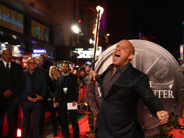 US actor Vin Diesel runs towards photographers holding a flaming sword as he arrives on the red carpet to attend the European premiere of the film The Last Witch Hunter. (AFP)