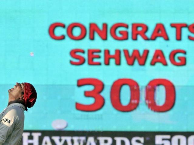 Sehwag laughs as a television screen behind congratulates him for scoring 300 against South Africa in Chennai on March 28, 2008. (AP Photo)
