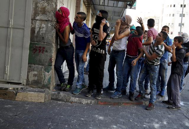 Palestinian protesters take cover behind a wall during clashes with Israeli troops in the West Bank city of Hebron October 21, 2015. Nearly 50 Palestinians have died in three-week long clashes with Israeli security forces. (REUTERS Photo)