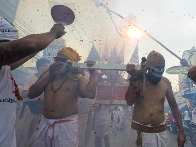Devotees to the Chinese shrine of Bang Liao have fireworks exploded over them as they carry a portable shrine during a street procession in Phuket. The festival is more than sprouts and tofu: it’s an assault on the senses, and for the most devout, on the body itself. (AP Photo/David Longstreath) (AP)