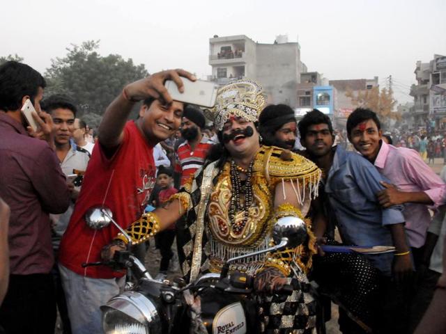 People take selfies with an artist playing the role of demon king Ravana as he arrives on a bike in Gurgaon’s New Colony on the occasion of Dussehra on Thursday. (Parveen Kumar/Hindustan Times)