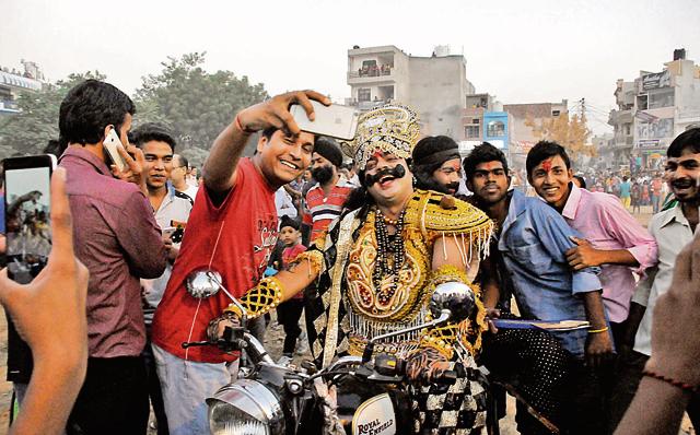 People take selfies with an artist dressed up as Ravana, as he arrives at the Ramlila on a bike , in New Colony on Thursday. (Parveen Kumar/HT Photo) People take selfies with an artist dressed up as Ravana, as he arrives at the Ramlila on a bike , in New Colony on Thursday. (Parveen Kumar/HT Photo)