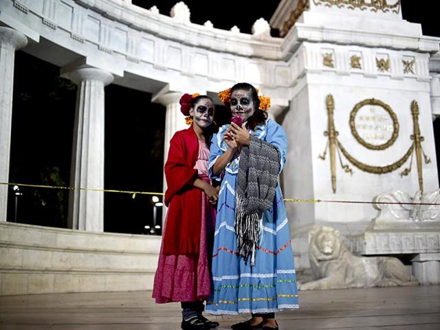 Woman with their faces painted as The Catrina look at a selfie taken during the Procession of the Catrinas in Mexico City on October 25, 2015. (AFP)