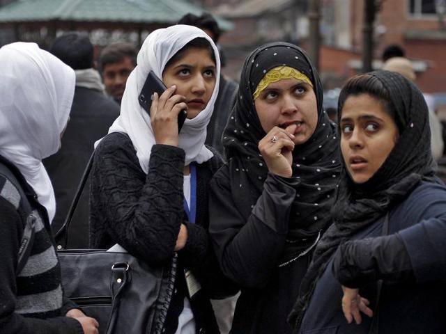 Kashmiri girls stand on a road divider after vacating their office buildings following an earthquake in Srinagar. (REUTERS)