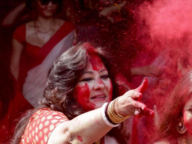 Bollywood actor and Indian lawmaker Moon Moon Sen, throws vermillion towards spectators during 'Sindoor Khela' or play of vermillion, a ritual during the Durga Puja festival in Kolkata, India , Sunday, Oct. 25, 2015. (AP Photo)