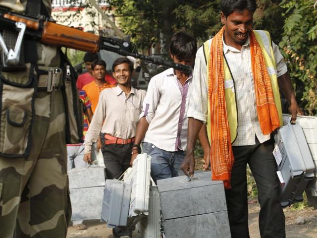 Polling officials share a light moment while carrying equipment under tight security in Patna. (Arvind Yadav/ HT Photo)