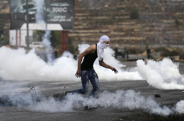 A Palestinian protester runs for cover from teargas fired by Israeli troops during clashes near the Jewish settlement of Bet El, near the West Bank city of Ramallah. (REUTERS) A Palestinian protester runs for cover from teargas fired by Israeli troops during clashes near the Jewish settlement of Bet El, near the West Bank city of Ramallah. (REUTERS)