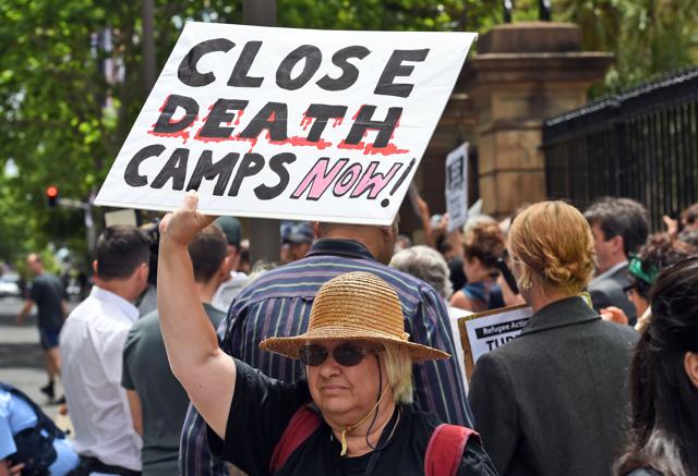 A pro-refugee protester (C) holds up a placard outside the Transfield Services annual general meeting in Sydney on October 28, 2015. (AFP Photo) A pro-refugee protester (C) holds up a placard outside the Transfield Services annual general meeting in Sydney on October 28, 2015. (AFP Photo)
