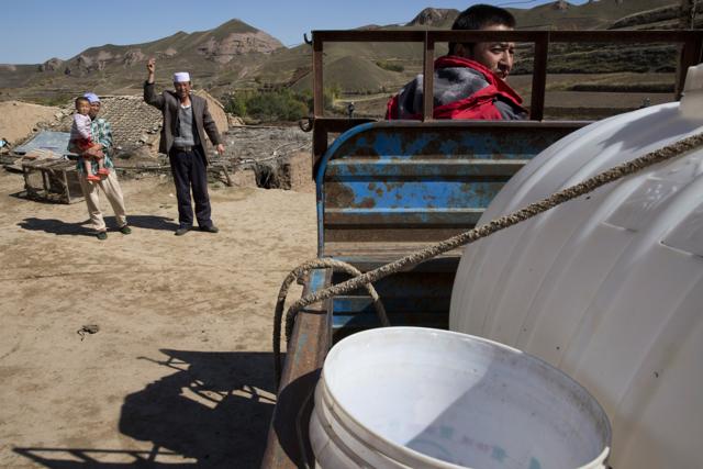 Yang Zhenjun, 48 waves as his son Yang Jingrong, right, leaves to fetch water for their home in Dacha village of Xiji county in northwestern China's Ningxia Hui autonomous region. (AP) Yang Zhenjun, 48 waves as his son Yang Jingrong, right, leaves to fetch water for their home in Dacha village of Xiji county in northwestern China's Ningxia Hui autonomous region. (AP)