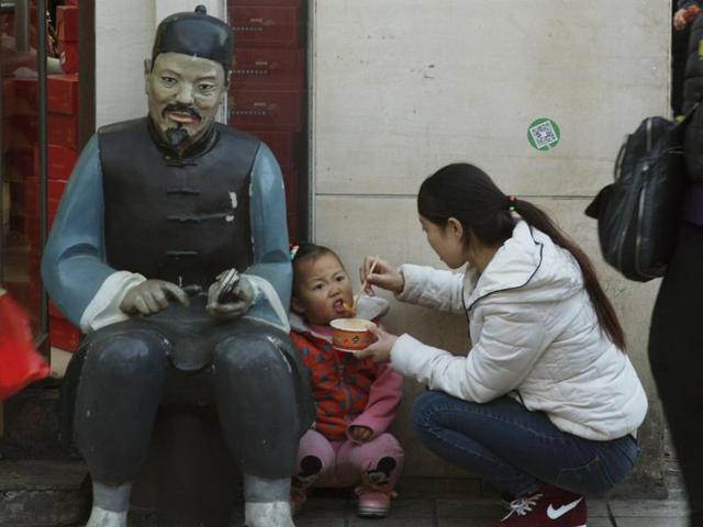 A woman feeds a child in Beijing, China. (AP) A woman feeds a child in Beijing, China. (AP)