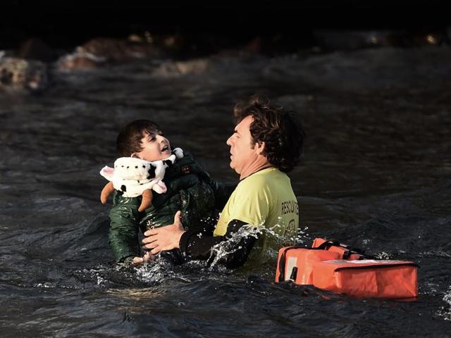 A Spanish lifeguard saves a migrant child as the boat he had boarded with other migrants and refugees sinks off the Greek island of Lesbos after crossing the Aegean sea from Turkey on October 30, 2015. (AFP) A Spanish lifeguard saves a migrant child as the boat he had boarded with other migrants and refugees sinks off the Greek island of Lesbos after crossing the Aegean sea from Turkey on October 30, 2015. (AFP)