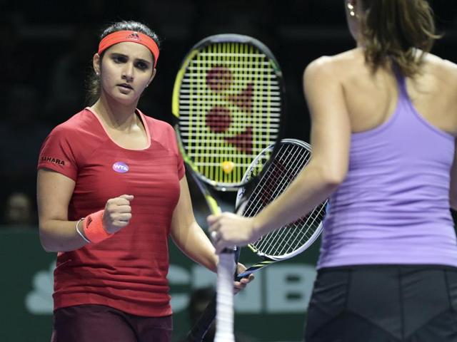 Sania Mirza, left, of India celebrates a point as she and partner Martina Hingis of Switzerland play Timea Babos of Hungary and Kristina Mladenovic of France during their match at the WTA Finals in Singapore on October 30, 2015.(AP)