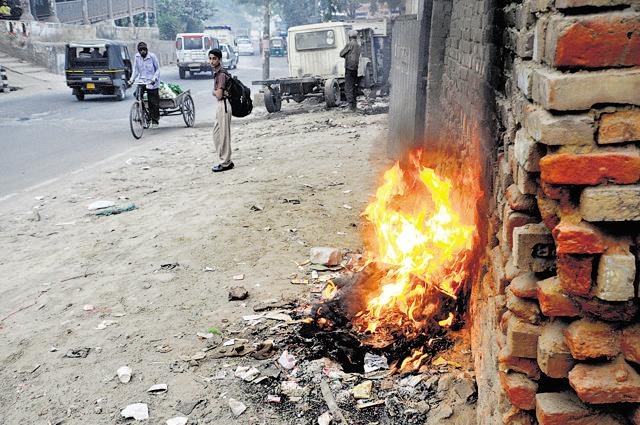 A schoolboy stands near a burning pile of waste at Raj Nagar Mod on the Gurgaon Expressway. (Parveen Kumar/HT Photo) A schoolboy stands near a burning pile of waste at Raj Nagar Mod on the Gurgaon Expressway. (Parveen Kumar/HT Photo)