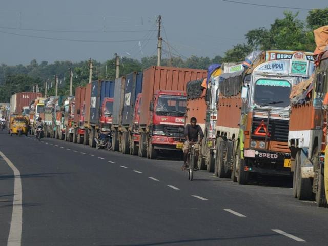 In this photograph taken on September 29, 2015, an Indian man cycles past parked Indian trucks carrying goods to Nepal near the India-Nepal border at Panitanki, some 40 kms from Siliguri. (AFP Photo)