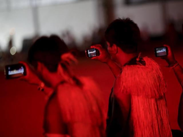 Indigenous men use mobile devices during the closing ceremony of the first World Games for Indigenous Peoples in Palmas, Brazil. (REUTERS) Indigenous men use mobile devices during the closing ceremony of the first World Games for Indigenous Peoples in Palmas, Brazil. (REUTERS)
