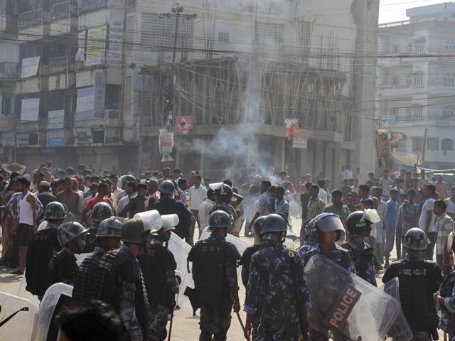 Ethnic Madhesi protesters stand near smoke from a tire set on fire by them, as Nepalese policemen stand guard near the Central Development Office at Birgunj, a town on the border with India, Nepal. (AP Photo)