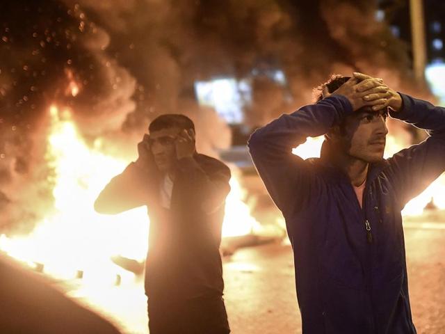 People react as smoke billows from burning pallets set on fire during clashes between Turkish riot policemen and Kurdish protesters in the southeastern city of Diyarbakir. (AFP)