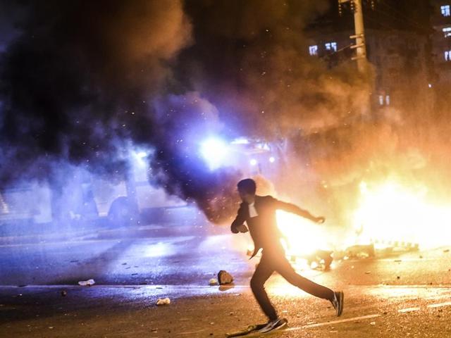 A man runs as smoke billows from burning pallets set on fire during clashes between Turkish riot policemen and Kurdish protesters in the southeastern city of Diyarbakir after first results of the Turkish general election showed a clear victory to the Justice and Development Party (AKP). (AFP)