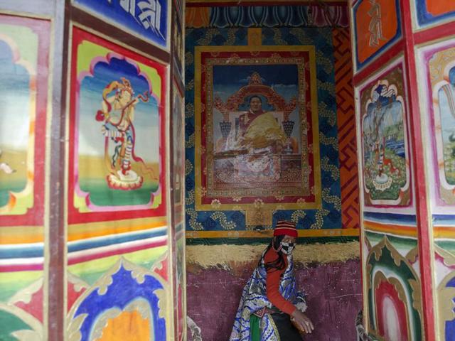An ethnic Tibetan woman walks under the picture of Khenpo Jigme Phuntsok behind prayer wheels at the Larung Wuming Buddhist Institute. Picture taken October 30, 2015. (REUTERS)