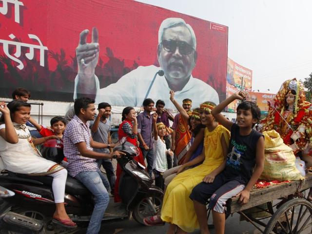 In poll-bound Bihar, an emphatic Nitish Kumar poster towers over children on their way to immerse idols during Durga Puja. (Arvind Yadav/ HT Photo) 
