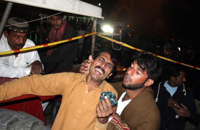 A man comforts a family member of a factory worker buried in rubble after the building collapsed in Lahore, Pakistan. (AP Photo)