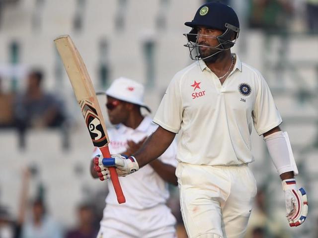 India's Cheteshwar Pujara raises his bat after scoring a half-century on the second day of the first Test against South Africa at The Punjab Cricket Association Stadium in Mohali on November 6, 2015. (AFP Photo) 