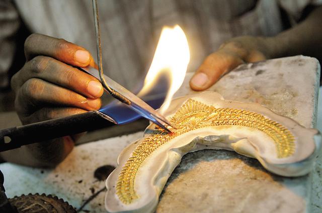 A goldsmith soldering gold in the frame of a necklace. (Photo by Saumya Khandelwal/ Hindustan Times) (Hindustan Times)