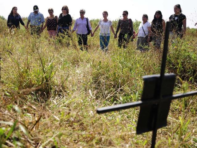 Relatives of missing people hold hands as they stand in an unofficial cemetery that is believed to have been used to bury about 150 bodies of crime victims near the town of Tetelcingo, Mexico. (AP Photo) Relatives of missing people hold hands as they stand in an unofficial cemetery that is believed to have been used to bury about 150 bodies of crime victims near the town of Tetelcingo, Mexico. (AP Photo)