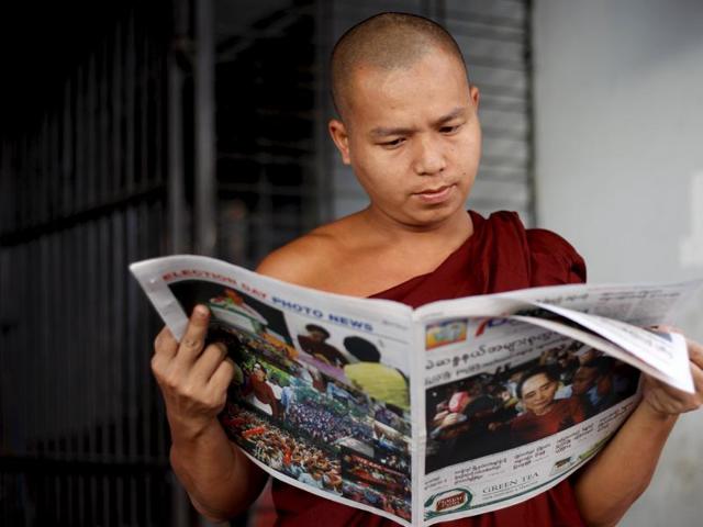 A Buddhist monk reads a newspaper on a street in Yangon. (REUTERS)